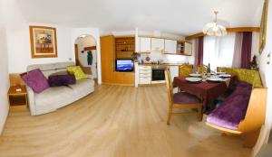 un soggiorno con tavolo e divano e una cucina di Villa Artic Apartments a Campitello di Fassa