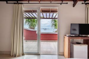 a room with a sliding glass door with a view of the ocean at Mata Hari Apartamentos in Búzios