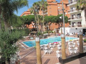 ein Schwimmbad mit Tischen und Stühlen neben einem Gebäude in der Unterkunft Hotel Reymar in Malgrat de Mar