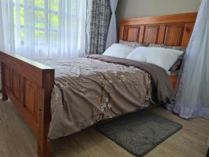 Lovely 3-Bed Apt @Palm Ridge next to Vipingo Ridge في Vipingo: غرفة نوم مع سرير مع اللوح الأمامي الخشبي ونافذة