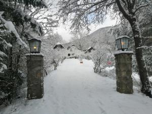Un camino cubierto de nieve con dos pilares de piedra con luces. en LANDSITZ OBERHOF petit hôtel, en Muggendorf