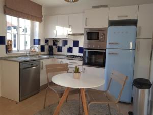 cocina con mesa, sillas y nevera en Penthouse Puro en Cabanas de Tavira