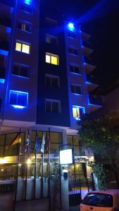 um edifício azul com bandeiras à frente à noite em La Bella Suit Otel em Kusadası