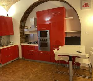 eine Küche mit roten Schränken und einem Tisch mit Stühlen in der Unterkunft Heart of San Lorenzo - La casa particular in Rom