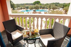 a balcony with chairs and a table with a view of a pool at I Giardini di Cala Ginepro Hotel Resort in Cala Liberotto