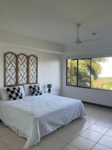 a white bedroom with a large bed and a window at Residence Nativa Las Vistas, appartement in Tarcoles