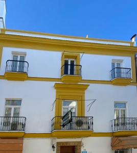 biały budynek z oknami i balkonami w obiekcie Hostal Manolo w mieście El Puerto de Santa María