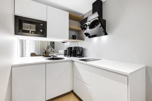 a white kitchen with white cabinets and a microwave at Bob W Tallinn City Centre - Ambassador in Tallinn +279 photos