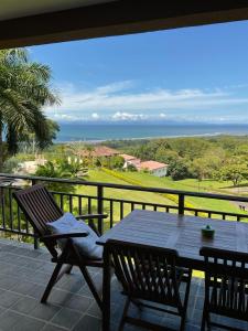 een tafel en stoelen op een balkon met uitzicht op de oceaan bij Residence Nativa Las Vistas, appartement in Tarcoles