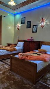 drie bedden in een kamer met blauwe verlichting bij Dar Calme Chez El Bouhali in Skoura