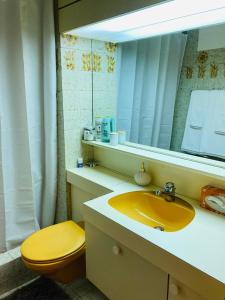 La salle de bains est pourvue d'un lavabo jaune et d'un miroir. dans l'établissement Your Pied-à-terre in Davos, à Davos