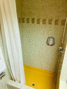 ducha con bañera amarilla y cortina de ducha en Your Pied-à-terre in Davos, en Davos