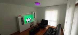 a living room with a tv and a black chair at Apartman Ivanović 5 in Soko Banja