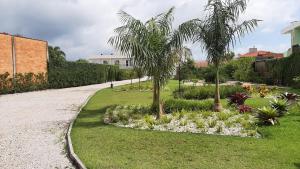 a garden with palm trees and flowers on a gravel road at Mix aparts Tijucas -kit 10 in Tijucas