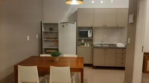 a kitchen with a wooden table and white cabinets at Mix aparts Tijucas -kit 10 in Tijucas