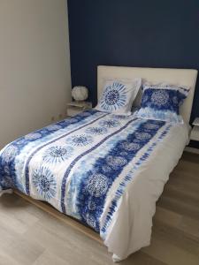 uma cama com um edredão e almofadas azuis e brancas em l oiseau bleu em Cayeux-sur-Mer