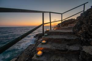 a set of stairs leading to the ocean at sunset at Villa Thalassa - Deja Vu Villas in Agios Nikolaos