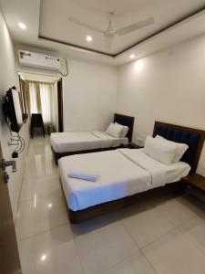 a hotel room with two beds and a television at Airport Regency in Devanhalli