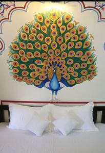 Golden Peacock Heritage Home Stay في جايبور: لوحة الطاووس على الحائط فوق السرير