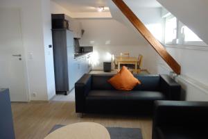 uma sala de estar com um sofá preto com uma almofada laranja em Ferienwohnungen Viersen em Viersen
