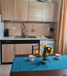 a kitchen with a table with a vase of flowers on it at Апартаменти-Студия в Комплекс Нестинарка in Tsarevo +36 photos