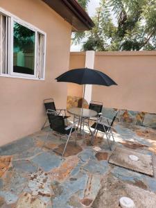 una mesa y sillas con una sombrilla en el patio en Janesis Holiday Homes, en Oyibi