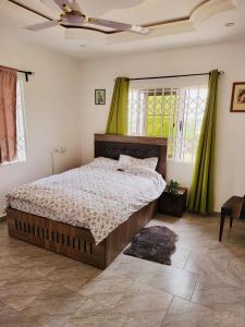 1 dormitorio con 1 cama y ventilador de techo en Janesis Holiday Homes, en Oyibi