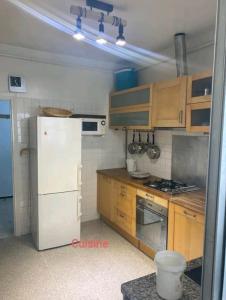 La cuisine est équipée d'un réfrigérateur blanc et de placards en bois. dans l'établissement Appartement RIM, à Casablanca