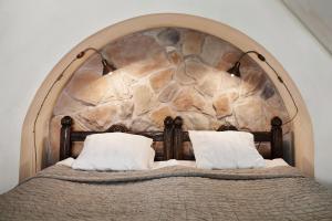 Una cama con una pared de piedra detrás. en Hotel Helgeand Wisby en Visby