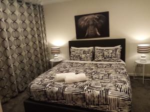 a bedroom with a black and white bed with two lamps at Gulf Harbour Guest House Apartment in Auckland