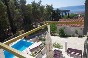 balcón con sombrilla y piscina en Holiday Home Nevista, en Sumartin
