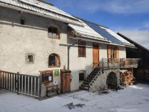 uma casa antiga com telhado coberto de neve e escadas em La Fruitière - Gîte d'étape et de séjour em Arvieux