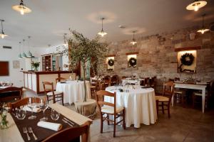 a restaurant with white tables and chairs and a brick wall at Casa Krasna Gourmet Boutique Hotel in Lokev