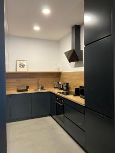 uma cozinha com armários pretos e um frigorífico preto em Mus Boavista no Porto