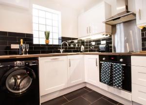 cocina con armarios blancos, lavadora y secadora en Kerns Cottage Stratford-upon-Avon en Stratford-upon-Avon