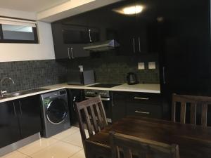 a kitchen with black cabinets and a table and a dishwasher at Scenic Apartment in Windhoek City Centre in Windhoek