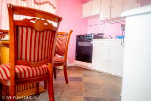 una cucina con pareti rosa, sedia e piano cottura di Belle View Apartment Villa - Hibiscus a Laborie