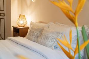 a bed with white pillows and a table with a lamp at THE SLOW vegan hotel in Mirissa