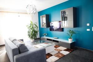 BIO Residence Apartments Timisoara في Uisenteş: غرفة معيشة مع أريكة والجدار الأزرق