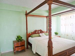 a bedroom with a canopy bed and a night stand at Belle View Apartment Villa - Cactus in Laborie