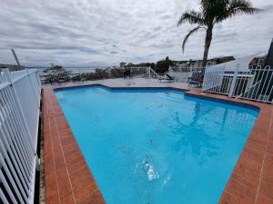 a large blue swimming pool with the ocean in the background at Nelson Towers Motel & Apartments in Nelson Bay