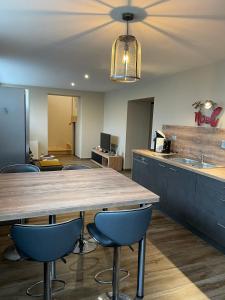 eine Küche mit einem großen Holztisch und blauen Stühlen in der Unterkunft Charmant logement avec balnéo in Wintzenheim