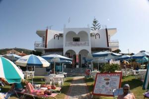 a building with umbrellas and people sitting in lawn chairs at Seashell Studios in Argasi