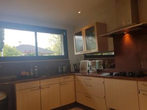 a kitchen with wooden cabinets and a large window at L'Escale du Monde in Vénissieux