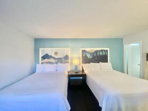 two beds in a hotel room with white sheets at Bluebird Day Inn & Suites in South Lake Tahoe