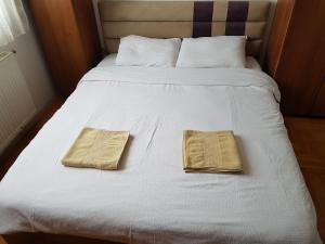 dos toallas están sentadas en una cama blanca en Redon Apartment, en Pristina