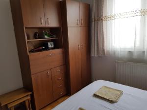 Schlafzimmer mit einem Bett, Holzschränken und einem Fenster in der Unterkunft Redon Apartment in Pristina