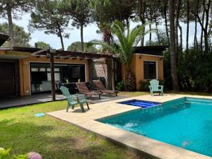 a backyard with a pool and chairs and a house at Casa Penelope Pinamar in Pinamar