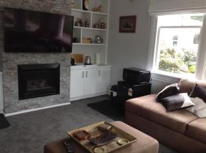 a living room with a couch and a fireplace at Aratahi Cottages - West Wing in Carterton