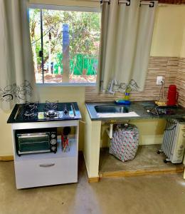 a kitchen with a stove and a sink and a window at Casa Estúdio com cozinha completa - Centro Serra do Cipó in Serra do Cipo
